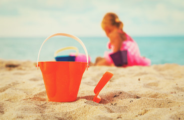 kids toys and little girl playing on beach