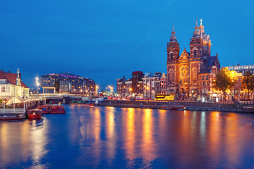 Fototapeta na wymiar Night city view of Amsterdam canal, bridge and Basilica of Saint Nicholas, Holland, Netherlands. Long exposure