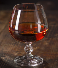 Glass of cognac on vintage wooden background. Low depth of field. 