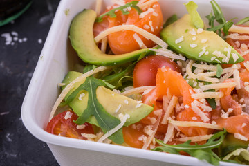 Avocado, salmon and cheese salad parmesan. With arugula and salad an iceberg with cherry tomatoes