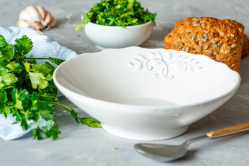 White plate for salad or soup, garlic, parsley, bread.