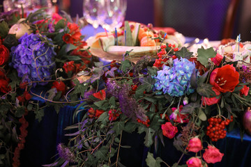 Obraz na płótnie Canvas Garland of roses, blue hydrangeas and greenery lies on dinner table