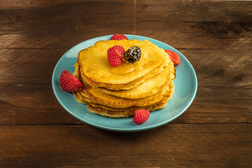 Honey poured over homemade pancakes with fresh fruit