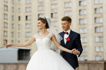 Groom holds bride like a dancer posing outside