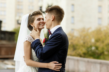 Groom touches bride's neck tender before a kiss