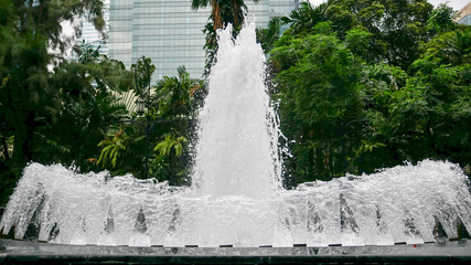 Close-up of fountain in the garden with background of buildings.