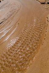 A small stream making a pattern in the sand on the beach in Spain