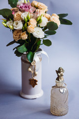 Vase with roses stands behind decorative glass bottle