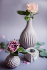 Little porcelain vase stands before tall porcelain vase on grey background