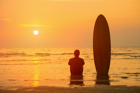 Vacation Concept ; Happy Asian surfer sitting with surfboards on the beach at sunset,Phuket,Thailand