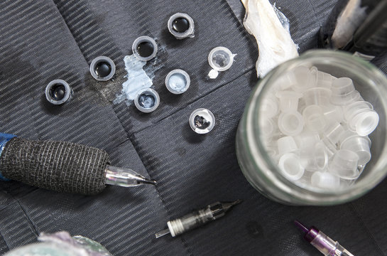 Tattoo Artist Table With Several Ink Small Cups And Pen Ink Machine