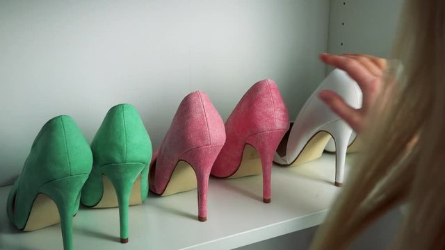 A blonde woman looks at high heel shoes on shelves