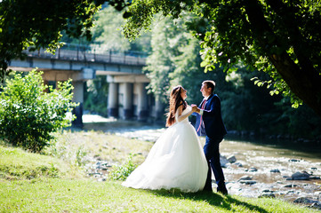 Lovely wedding couple at amazing landscapes stay against mountain river.