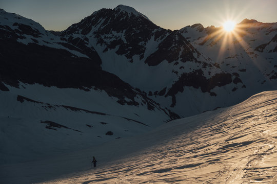Snowboarder going up mountain in sunrise light