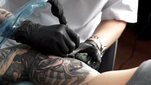 Master tattoo draws the black paint on the clients tattoo.