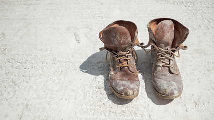 Old brown work boots covered in concrete worn by a woman