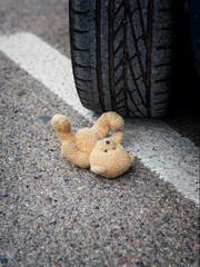toy bear in the blood under the car wheels