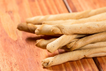 Pile of saulty grissini sticks on the wooden planks background