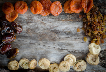 Assorted dried apricots, figs, dates and raisins on aged wood with copy space.