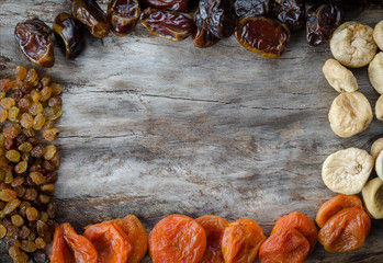 Assorted dried apricots, figs, dates and raisins on aged wood with copy space.