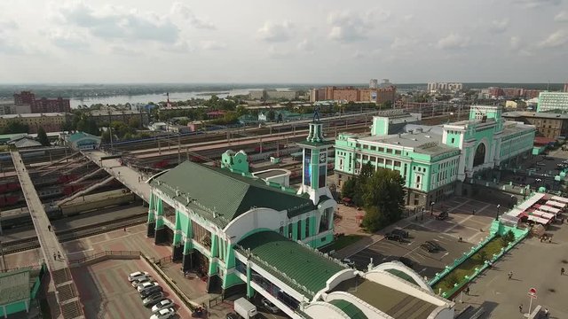 Novosibirsk Main Railway Station Green facade. Russia Siberia Railway tracks of train. View of city from great height. People go. Summer spring warm light day. 4k Aerial drone Flight over the station