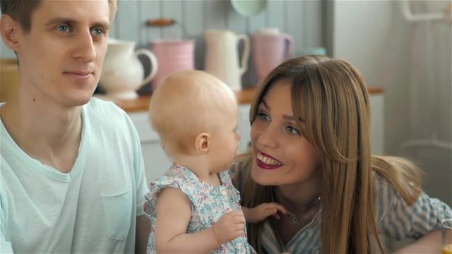 Hispanic father and mother smiling at baby, on kitchen morning, happy family