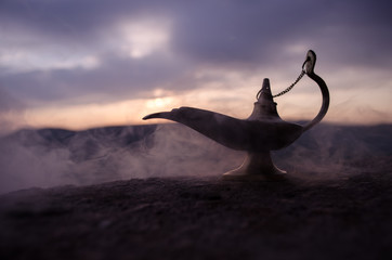 Antique artisanal Aladdin Arabian nights genie style oil lamp with soft light white smoke. Sunset...