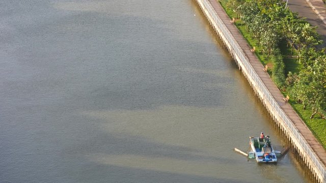 Unidentified janitor is working on river in Ho Chi Minh city. Ho Chi Minh is the biggest city in Viet Nam