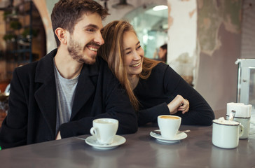 Young happy hipster couple in love having dating in a cafe. drink coffee,  talk and smile. Lifestyle. Relations between man and woman.