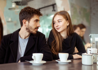 Young happy hipster couple in love having dating in a cafe. drink coffee,  talk and smile. Lifestyle. Relations between man and woman.