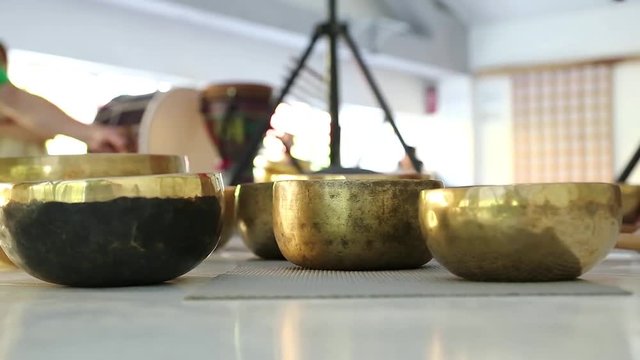 Master-class with Tibetan singing bowls, musical group plays on Tibetan singing bowls. Man operating with Tibetan singing bowls