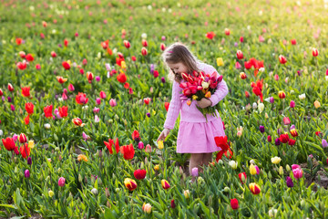Naklejka na ściany i meble Little girl in tulip flower garden