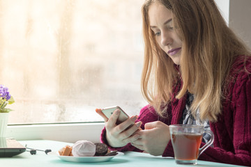878187 Young woman at cafe drinking and using mobile phone in sunday morning