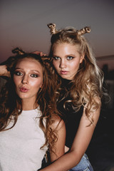 Obraz premium lifestyle and people concept: Fashion portrait of two stylish girls best friends wearing jeans skirts, outdoors on the roof. Happy summer time for fun.