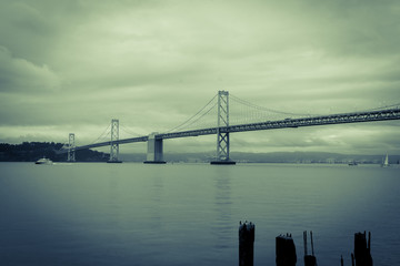 San Francisco Oakland Bay Bridge across bay in split tone image with vignette.