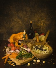candle against the background of vegetables, chopped cabbage, a wine bottle, a glass with wine, an ancient background, vegetables, the cut pumpkin, a wooden mortar, a wooden bowl, the ancient tool