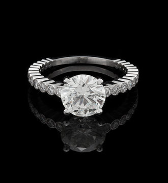 Engagement ring, big round brilliant with side stones on black reflective background