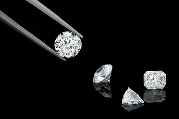 loose brilliant diamonds, round, trillion, and radiant / emerald on reflective black background one...