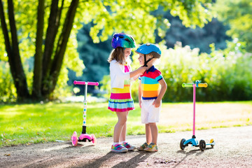 Kids riding scooter in summer park.