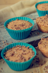 Chocolate muffin with soft cream and fresh blueberry powdered with sugar, cup of coffee, rustic background