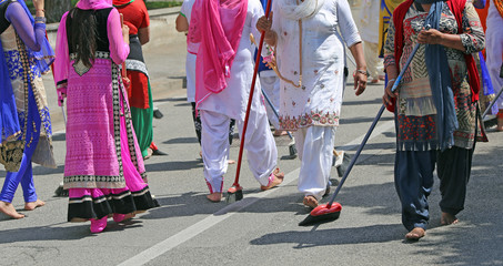 Sikh women while scavenging the street with a broom during a fes