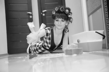 Woman in curlers washes floors at home