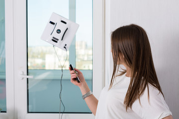 Woman cleaning windows with robotic cleaner