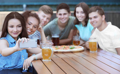 Happy friends taking selfie in cafe