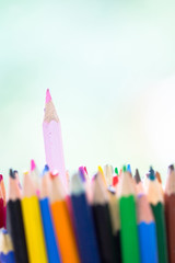 Pink wooden pencil stick out in stack of other color pen as unique, innovation, distinguish, creativity, artistic, colorful background