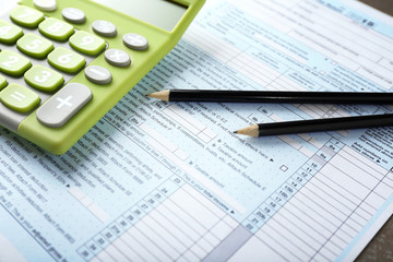 Green calculator with documents on table. Tax concept