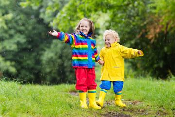 Fototapeta premium Kids play in rain and puddle in autumn