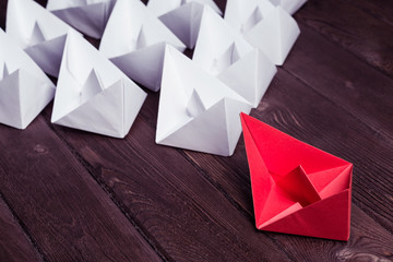 Business leadership concept with white and color paper boats on 