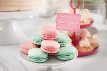 Stand with tasty macarons on table served for party