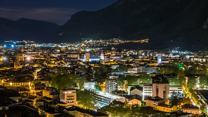 Sustainable city, colorful lights and traffic at night in mountain valley, Trento, Italy